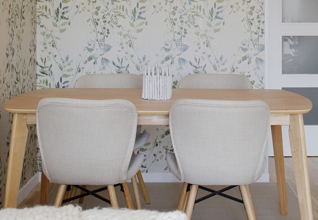 Trabajo de interiorismo que muestra una mesa de comedor con una pared con papel pintado