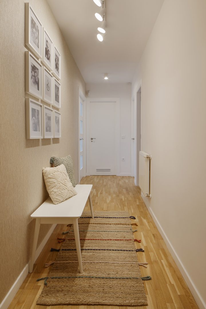Pasillo con banco, alfombra y cuadros diseñado en proyecto de interiorismo