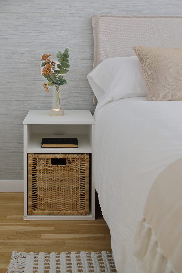 Mesita de noche con cesta en dormitorio diseñado en proyecto de interiorismo