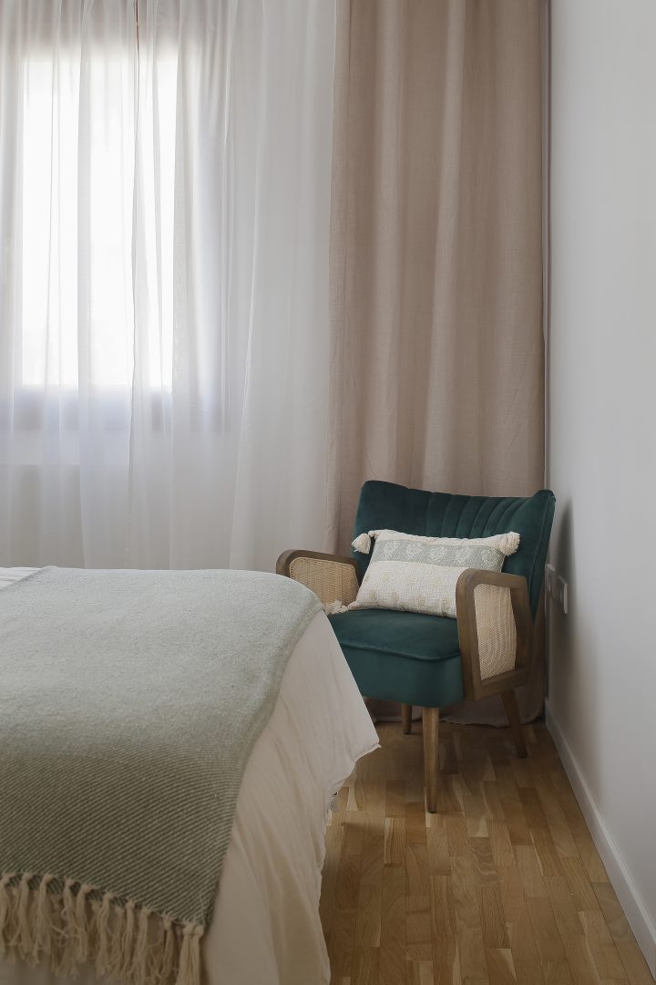 Rincón de dormitorio con butaca verde diseñado en proyecto de interiorismo