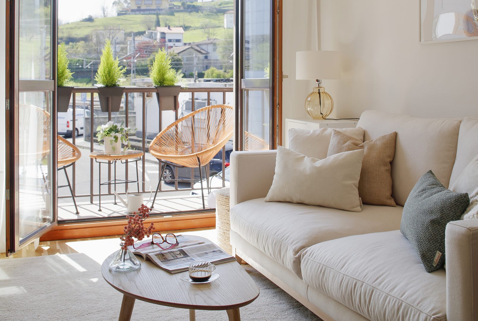 Espacio de sofá en salón diseñado en proyecto de interiorismo con balcón abierto al fondo